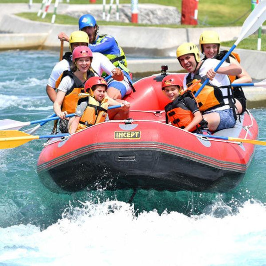 Group of people river rafting in a red inflatable boat, wearing helmets and life jackets